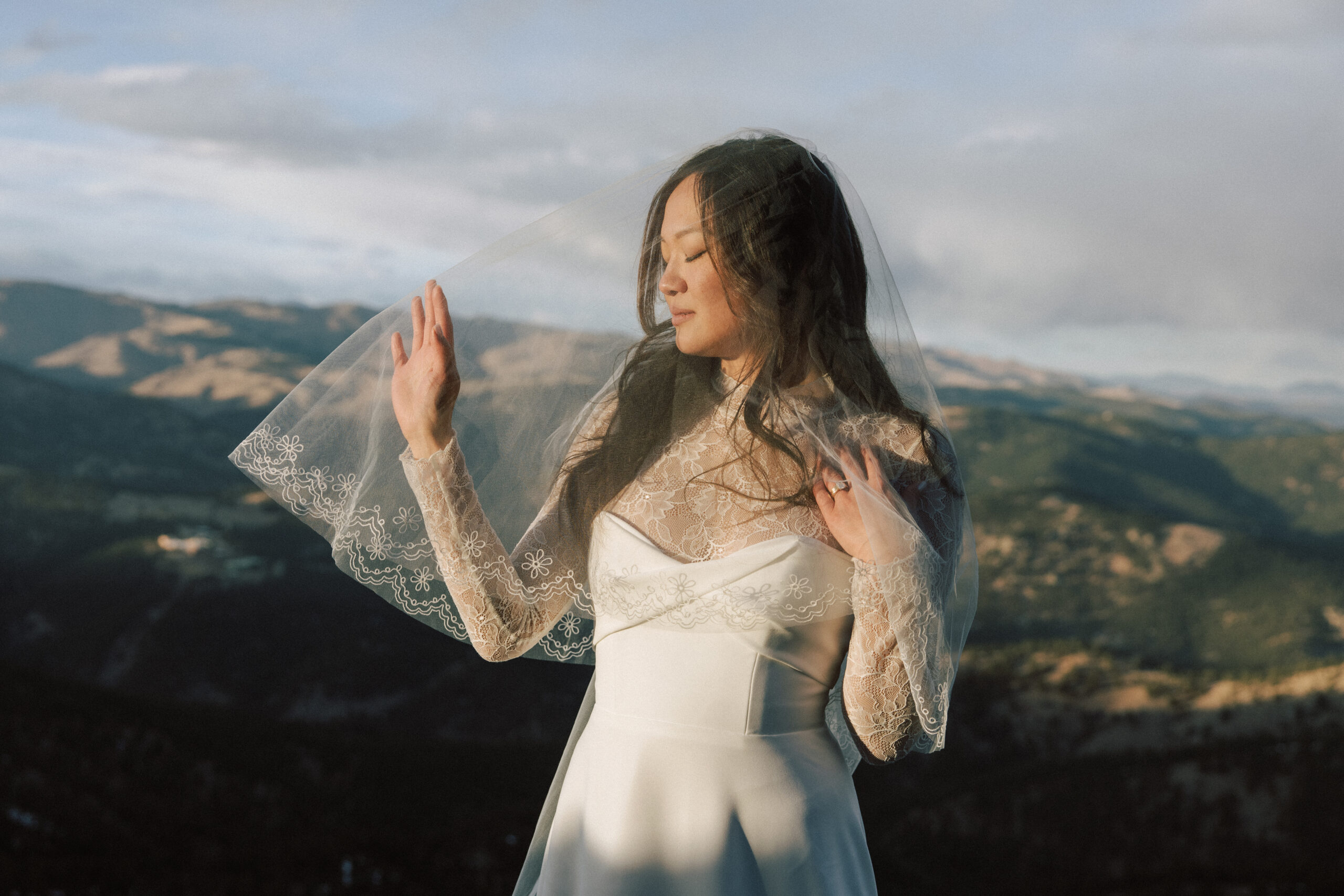 Bride under veil bathed in Golden light with Colorado front range behind her