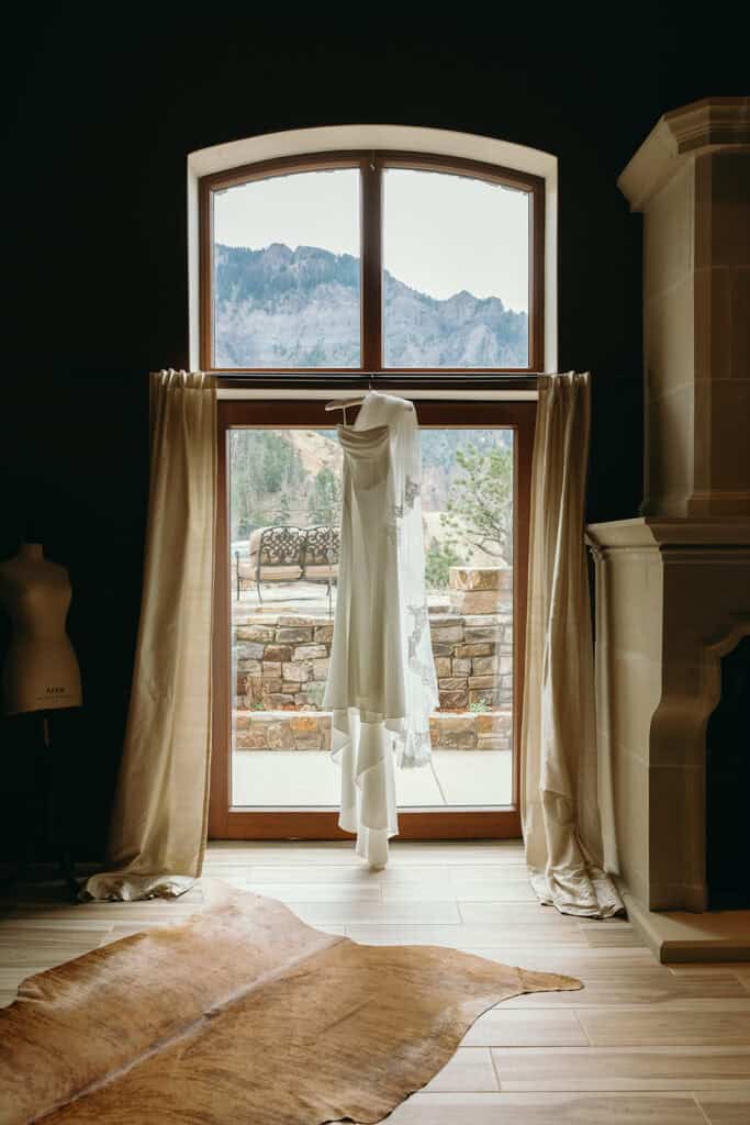 the bride's dress hangs in front of the bridal suit window at Gold Mountain Ranch